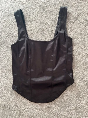 Svart korsett liknande topp - En svart topp från H&M som är lite korsett liknande. Skriv om du har några frågor💕