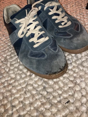 Mörkblå sneakers med mockadetaljer - Snygga mörkblå sneakers med beige snörning och detaljer i mocka och tyg. Skorna har en klassisk låg profil och gummisula. Perfekta för dig som gillar retrostil och vill ha något som sticker ut lite extra.