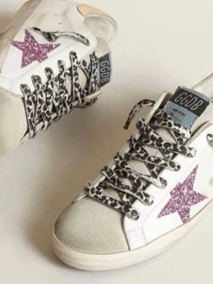 Golden goose💖 - Snygga vita sneakers från Superga med rosa glitterstjärna på sidan och leopardmönstrade skosnören. Skorna har beige detaljer vid tån och hälen samt en klassisk låg siluett. Perfekta för dig som vill sticka ut med coola detaljer.