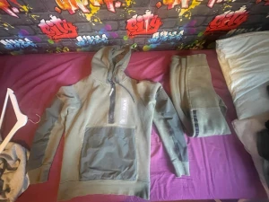 Grönt Air Max set med huva - Säljer ett grönt set från Nike Air Max med hoodie och matchande byxor. Hoodien har dragkedja vid halsen, stor ficka framtill och tryckt Air Max-logga. Byxorna har resår i midjan och detaljer i mörkare grönt längs sidorna. Perfekt för en avslappnad och sportig stil.