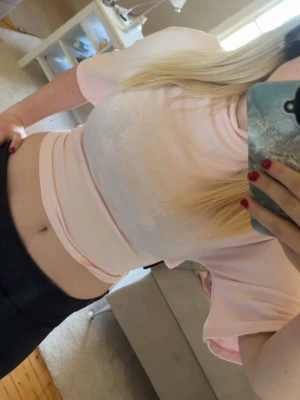 Ljusrosa croppad topp med knyt - Söt ljusrosa croppad topp med korta ärmar och knyt i ryggen. Toppen har en mjuk och stretchig känsla och passar perfekt till höga byxor eller kjol. Enkel men ändå stylish design som ger en feminin vibe.