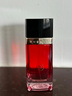 Bugatti Eleganza Rossa parfym 60ml - Bugatti Eleganza Rossa är en Eau de Parfum för henne i en elegant röd kartong med geometriskt mönster och gulddetaljer. Förpackningen rymmer 60 ml och har en lyxig och modern design som känns exklusiv och stilren.