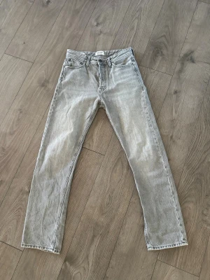 Ljusgrå jack&jones jeans - Säljer ett par ljusgrå jeans med rak passform och klassisk femficksdesign. Jeansen har normal midja och är tillverkade i denim. Perfekta för en avslappnad och trendig look.