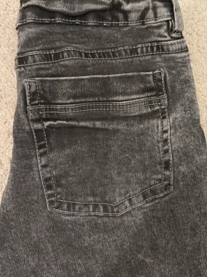 Grå bootcut jeans med tvättad look - Säljer ett par grå jeans med bootcut-modell och tvättad finish. Jeansen har klassiska fem fickor och LÅG midja. Materialet är denim i bomull och de har en avslappnad men ändå snygg passform. Perfekta för dig som gillar en lite retro vibe. De är sjukt snygga och lowwaist!! Är storlek 158 men skulle säga att de passar xs! Passade mig när jag var ca 161 cm! De är använda men de har inte slitits! Skriv privat för mått eller frågor!
