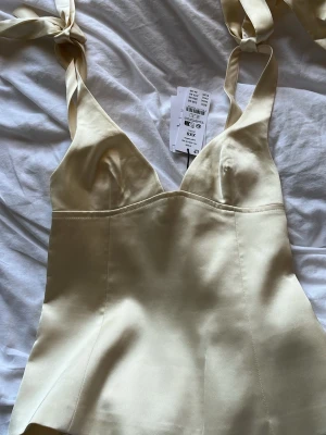 Champagnefärgad satinlinnetopp - Supersnygg ljusgul linnetopp i satin och figurnära passform. Perfekt för att lyfta vilken outfit som helst. Dragkedja baktill. Aldrig andvänd! 