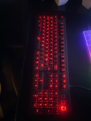 Svart gamingtangentbord med röd belysning - Säljer ett svart gamingtangentbord med snygg röd LED-belysning. Tangentbordet har fullstora tangenter och numerisk del, perfekt för gaming eller arbete vid datorn. Ansluts med kabel och har en robust plastkonstruktion.