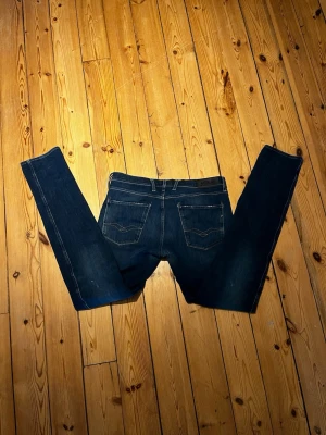 Mörkblå jeans från replay!! - Säljer ett par mörkblå jeans från replay med klassisk femficksdesign och kontrastsömmar. Jeansen har rak passform och är tillverkade i denim med lätt tvättad look. Perfekta för en avslappnad och stilren outfit det ända felet är att gylfen har lossnat från ena sidan annars typ helt nya 