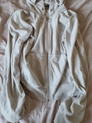 Vit hoodie från Gina Tricot - Mysig vit  hoodie från Gina Tricot i storlek XS. Hoodien har dragkedja framtill, två fickor och en klassisk huva med snörning. Perfekt för en chill och avslappnad stil. Materialet känns mjukt och skönt mot huden.