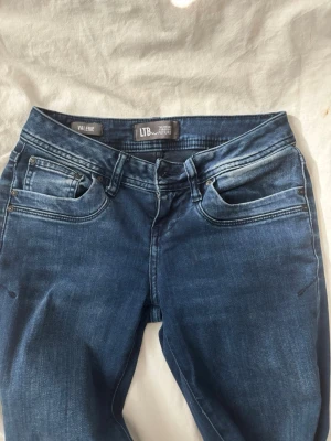 Blå jeans från LTB Valerie - Snygga blå jeans från LTB i modellen Valerie. Jeansen har klassisk femficksdesign, normal midja och smal passform. Materialet är mjukt och stretchigt denim som ger en bekväm känsla. Fina slitningar och detaljer vid fickorna för en trendig look.