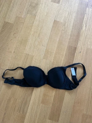 Svart push-up bh från Wolford - Snygg svart push-up bh från Wolford med lätt vadderade kupor och diskret randigt mönster. Bh:n har spetsdetaljer upptill och justerbara axelband. Tillverkad i mjuk polyamidblandning för en bekväm känsla.