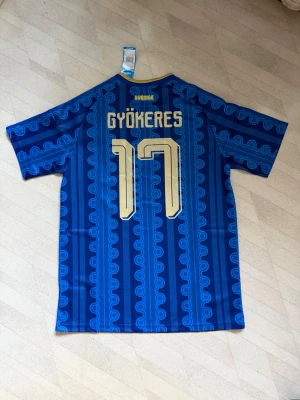  Sverige fotbollströja  - Säljer en blå fotbollströja från Adidas med Sveriges landslagsmärke och Gyökeres namn, säljer den för den va för stor för mig så den är oanvänd, skriv vid frågor 