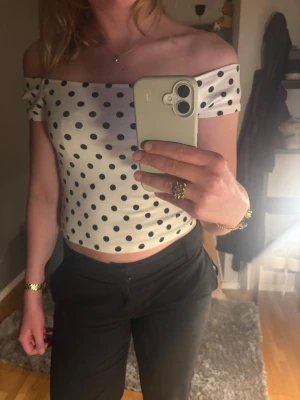 Prickig offshoulder topp - Säljer en vit offshoulder topp med svarta prickar. Toppen är croppad och har en tight passform.  Använd ca 2 gånger säljer då den inte kommer till användning 