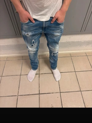 Blå slitna jeans dondup - Säljer ett par ljusblå dondup jeans med slitningar och hål på både lår och knän. 