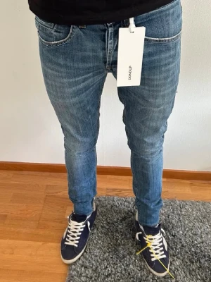 Dondup George  - Säljer ett par Dondup George-jeans i storlek 30/30. Jeansen är i mycket fint skick, 9–10, och sparsamt använda. Nypris ca 2 000–3 000 kr. Snygg passform och hög kvalitet. Benlängden är ca 96 cm och midjemåttet är ca 38 cm. Han på bilden är ca 175-180 cm. Hör av dig vid frågor eller för fler bilder. 