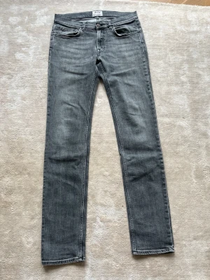 Grå raka jeans från Acne Studios - Snygga grå jeans från Acne Studios med rak passform och klassisk femficksdesign. Jeansen har en diskret tvättad look och är tillverkade i mjukt denimtyg. Perfekta för en avslappnad och trendig stil.