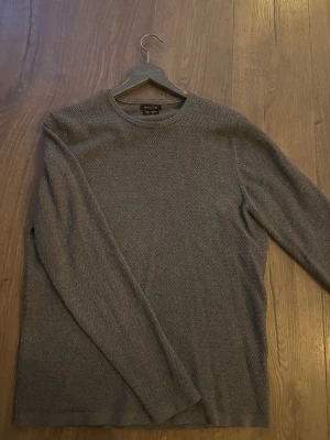 Grå stickad tröja Massimo Dutti - Säljer en grå stickad tröja från Massimo Dutti i bomull. Tröjan har ett diskret mönster, rund halsringning och långa ärmar. Perfekt för dig som gillar stilrena och bekväma plagg med en lyxig känsla. Passar S-M. Hör av dig vid minsta fundering.