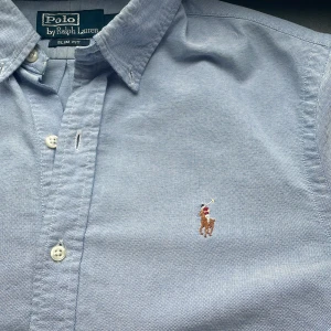 Skjorta Polo Ralph Lauren  - Klassisk ljusblå skjorta från Polo Ralph Lauren i slim fit-modell. Inget fel på den och kommer med en Polo Ralph Lauren bag som är mörkblå😁Använd vid 2 tillfällen, hör av er vid minsta fundering 💛
