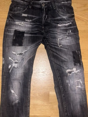 D.squared.2 Svarta slitna jeans  - Säljer ett par svarta jeans med tydliga slitningar samt svarta patchar på flera ställen. Perfekta för dig som gillar unik,stilig och trendig streetstil.inga skador‼️😊