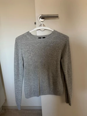 Grå stickad tröja från Uniqlo - Säljer en enkel och stilren grå stickad tröja från Uniqlo. Tröjan har rund halsringning, långa ärmar och är gjord i mjukt material som passar perfekt till lager på lager. Klassisk modell som funkar till det mesta.