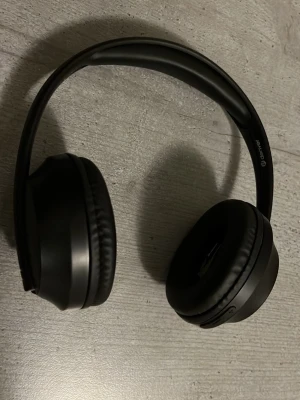 Svarta trådlösa hörlurar från Denver - Snygga svarta over-ear hörlurar från Denver med mjuka öronkuddar och justerbar båge. Hörlurarna är tillverkade i plast och har en stilren, matt finish. Perfekt för musik och gaming med trådlös anslutning.