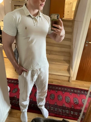 Vit pikétröja Polo Ralph Lauren  - Klassisk vit pikétröja från Polo Ralph Lauren i modellen Custom Slim Fit. Tröjan har korta ärmar, krage och knappar framtill samt den ikoniska broderade loggan på bröstet. Tillverkad i mjuk bomull som andas.