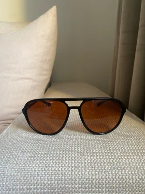 Svarta solglasögon herr - Dolce & Gabbana - Snygga svarta aviator-solglasögon från Dolce & Gabbana med bruna tonade glas. Ramen är i svart syntetmaterial och har en klassisk look.  Köpta för 3 år sedan - modellen säljs inte längre.  Använda endast ett fåtal gånger - som nyskick.  Nypris: 3000kr   Original påse samt original fodral medföljer.