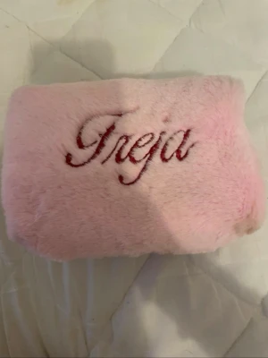 Rosa fluffig necessär med brodyr - Söt rosa necessär i mjukt, fluffigt material med broderad text 'Freja' i rött. Perfekt för smink eller småprylar. Stängs med dragkedja och har en kompakt, rektangulär form som är lätt att ta med sig. Är lite smutsig på undersidan(se sista bild) men inget som påverkar. Skriv om du har frågor eller undrar nåt!