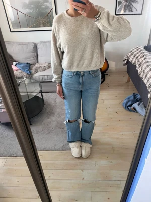 Högmidjade jeans från Stradivarius - Högmidjade jeans från stradivarius med hål i knänen! Ena skärphållaren har släppt som man ser på bild 4!