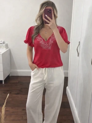 Rosa vintage blus med vit brodering & midjedetalj från time, strlk L - En söt rosa vintage blus med vita blombroderi & snörning i midjan som detalj från märket time i storlek L. Snörningen knyter man antingen på framsidan eller baksidan. Den är köpt secondhand (för 150kr) men har aldrig kommit till användning. Den är i 100% Bomull. FÖRST TILL KVARN! SISTA CHANSEN!