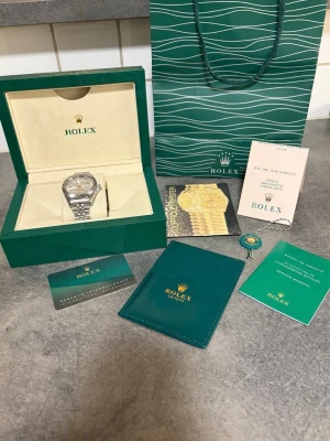 Herr klocka - fullsett  - Modell: Datejust Skick: Ny, Oanvänd  Utförande: Oysterlänk i stål, räfflad bezel, ljus urtavla Storlek: 36 mm Tillbehör: Komplett set – originalbox, certifikat, manualer, tags och påse