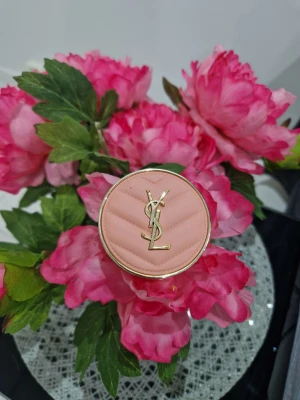 YSL Make Me Blush puderrouge - Lyxigt puderrouge från Yves Saint Laurent i nyansen Make Me Blush. Kommer i en rund, rosa dosa med guldfärgade detaljer och YSL-logga på locket. Perfekt för att ge kinderna en fräsch, rosig ton. Innehåller 6 g och är tillverkad i Italien.