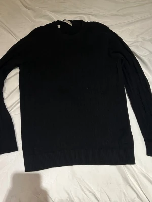 Svart kabelstickad tröja Selected Homme - Säljer en svart kabelstickad tröja från Selected Homme. Tröjan har rund halsringning, ribbade muddar vid ärmslut och nederkant samt ett klassiskt kabelstickat mönster. Perfekt för dig som gillar stilrena och tidlösa plagg.