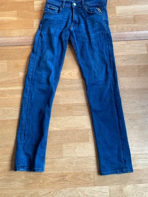Blå jeans från Replay - Säljer ett par klassiska blå jeans från Replay med smil passform och fem fickor. Jeansen har snygga kontrastsömmar och en patch med Replay-logga bak i midjan. Tillverkade i mjukt denimtyg som sitter skönt hela dagen.pris kan diskuteras.