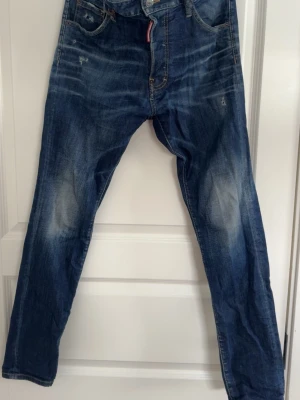 Blå Dsquared jeans med slitningar - Riktigt sköna dsquared2 jeans inköpta på United Fashion för 6499kr drygt två år sedan, riktigt bra skick och i size 44 italiensk, drygt 29 waist, jag väger 75kg och är 183cm o sitter bra på mig. Söker bud på de så skriv gärna i dm!
