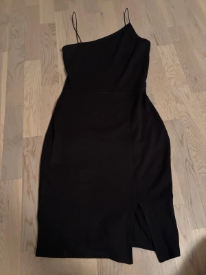 Svart klänning med slits - Säljer en jättefin svart klänning med smala axelband och slits framtill. Perfekt för sommar och fest. Använd en gång🖤