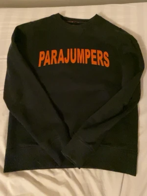 Svart sweatshirt från Parajumpers - Cool svart sweatshirt från Parajumpers med stor orange logga över bröstet. Klassisk rund halsringning och ribbade muddar vid ärmslut och nederkant. Perfekt för en avslappnad och trendig look.