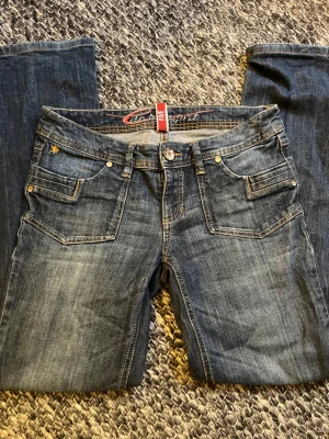 Blå Five Jeans med raka ben - Snygga blå jeans från Five med raka ben och klassisk femficksmodell. Jeansen har dekorativa sömmar, dubbla fickor fram och bakfickor med lock och knapp. Tillverkade i slitstarkt denim med lätt tvättad look och detaljer i metall. Storlek W31  L32