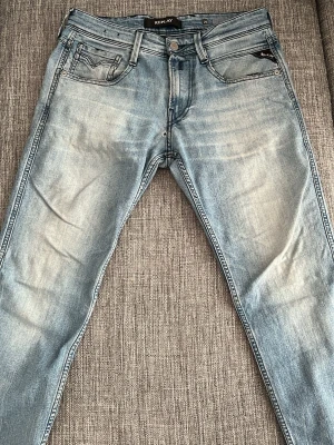 Ljusblå Replay jeans  - Snygga ljusblå jeans från Replay med klassisk femficksmodell och tvättad finish. Jeansen har raka ben och detaljerade sömmar, samt Replay-logga på myntfickan. Perfekta för en avslappnad och trendig stil. Den har ett litet hål som man kan se i första bilden. Säljer för 199kr priset kan diskuteras 