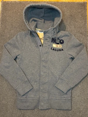 Vintage Hollister Cardigan Med Knappar & Zip - Säljer denna mycket snygga och unika Hollister cardigan med både zip och knappar! | Storlek S | Längd ≈ 65-66cm Bredd armhåla - armhåla 53-54cm | Modell 175cm, 68 kg|  Hör gärna av vid funderingar!