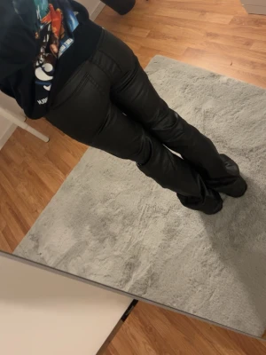 Svarta bootcut jeans i skinnimitation - Säljer ett par svarta bootcut jeans i skinnimitation med låg midia i nytt skick💕