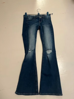 Blå bootcut jeans med slitningar - Jag har två par av dessa jeans och säljer de paret som jag inte har öppnat ur påsen. Så den är i helt nytt skick och tog bara bild på jeansen jag har redan öppnat. Men skickar jeansen som är helt nya 