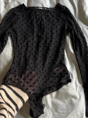 Svart meshbody med prickar från Bik Bok - Säljer en svart långärmad body från Bik Bok i meshmaterial med små sammetsprickar över hela plagget. Använd fåtal gånger 