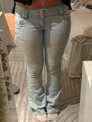 Ljusblå lågmidjad bootcut jeans - Säljer ett par ljusblå bootcut jeans då dom sitter lite tajt. De är i storlek M. De är lite urtvättade och flammiga vid knäna