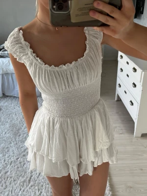 Vit studentklänning - Säljer denna vita klänning från Princess Polly som bara använts två gånger. Superfin och skön och ”inbyggda shorts” då understa lagret av kjolen går ihop mellan benen. Man kan även välja själv hur man vill ha den på axlarna. Den är i perfekt skick förutom en liten slitning på ryggen som syns på en av bilderna🫶