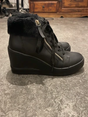 Svarta skor med klack Anna Field - Snygga svarta skor med klack, snörning och dragkedja i guld på sidan. Ovandelen är i konstläder och kragen är fodrad med mjuk svart fuskpäls. Perfekta för dig som vill ha både stil och komfort. Endast använda en gång då jag inte kan gå i för hög klack