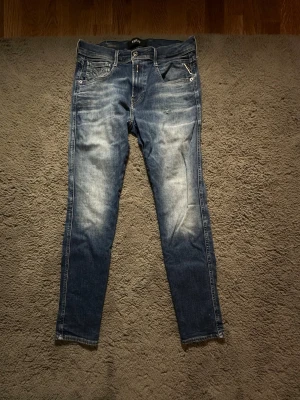Blå slim fit jeans från Replay - Snygga Replay jeans som inte längre passar. De har ett litet hål på vänster lår. Storlek: Midja 29 Längd 32