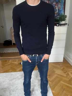 J Lindeberg tröja - En stilren marinblå stickad tröja från J Lindeberg i storlek M. Tröjan är mindre i storleken så passar även S. Det finns inga tecken på användning och skriv vid fundering!🙌☀️