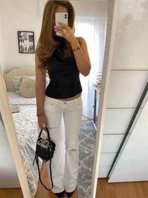 Vita utsvängda jeans med slitningar - Snygga vita jeans med utsvängda ben och slitningar vid knäna. Jeansen har klassisk femficksdesign och låg midja. Perfekta för en trendig och avslappnad look.