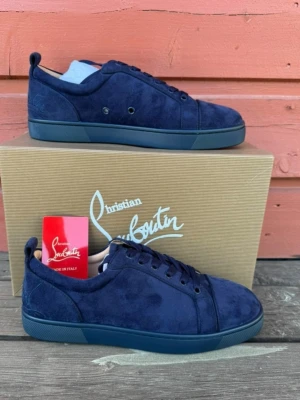 Christian louboutin skor loubs  - Snygga blåa sneakers från Christian Louboutin med ikoniska röda sulor och signatur på undersidan. Skorna är gjorda i mocka med klassisk snörning och låg profil.Ej autentisk. Perfekt för dig som vill sticka ut med exklusiva detaljer och stilren design.