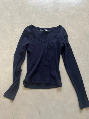 Mörkblå långärmad topp med v-ringning - En stilren mörkblå långärmad topp med v-ringning och smal passform. Tillverkad i mjukt material, perfekt för att matcha med jeans eller kjol. Enkel och klassisk design utan extra detaljer.